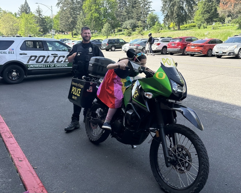 kid on UOPD motorcyle with officer and police car